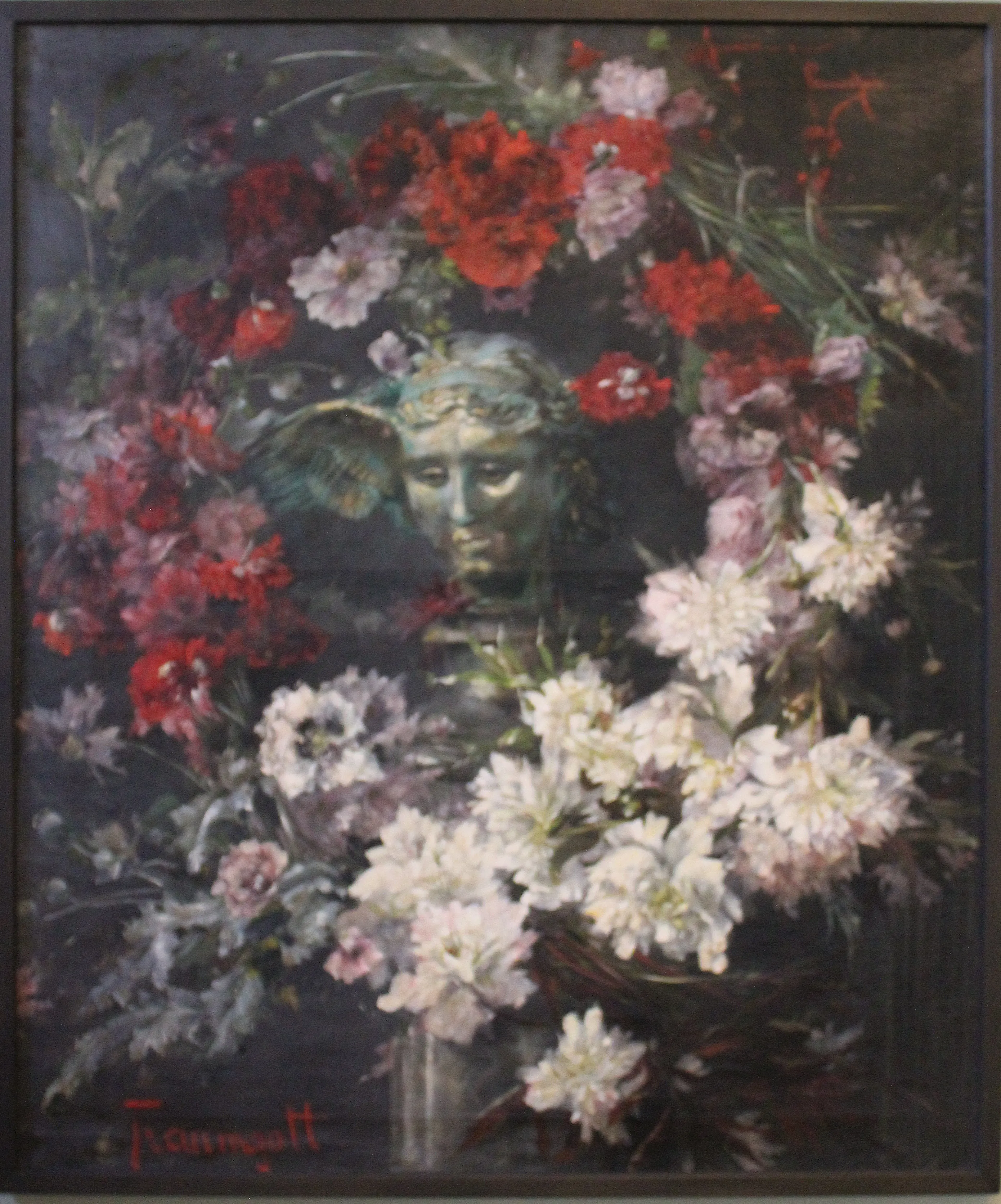 A weathered antique head of a winged god, greenish as old bronze, ringed by heaped red and white carnations and peonies against a dark ground.